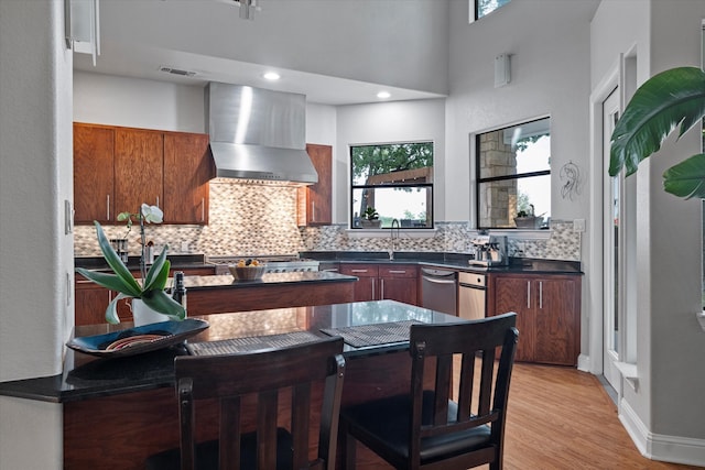 kitchen featuring dark countertops, visible vents, light wood-style flooring, backsplash, and wall chimney exhaust hood