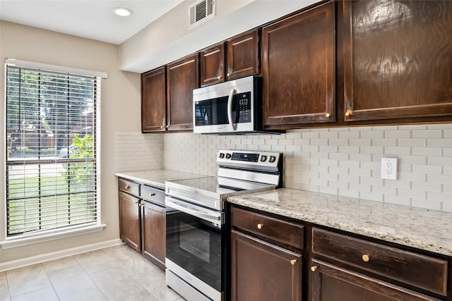 kitchen with dark brown cabinets, tasteful backsplash, light stone countertops, electric range oven, and light tile patterned floors