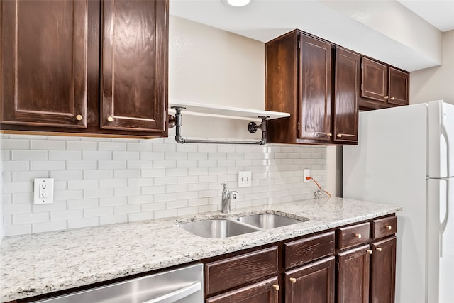 kitchen with stainless steel dishwasher, dark brown cabinetry, tasteful backsplash, white fridge, and sink