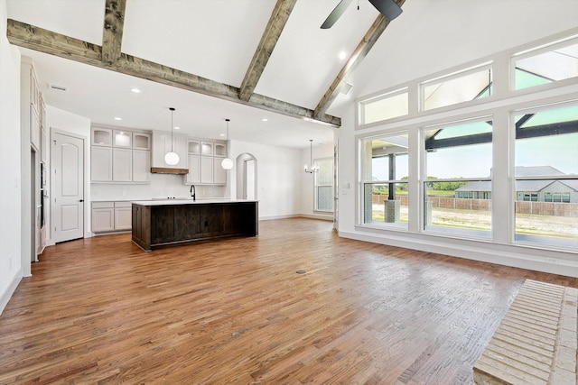 kitchen featuring a large island, hanging light fixtures, beamed ceiling, hardwood / wood-style floors, and ceiling fan with notable chandelier