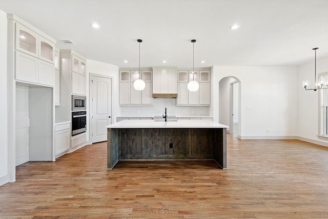 kitchen featuring custom exhaust hood, sink, white cabinets, an island with sink, and stainless steel appliances