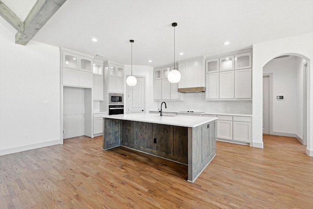 kitchen with black appliances, white cabinetry, and a kitchen island with sink