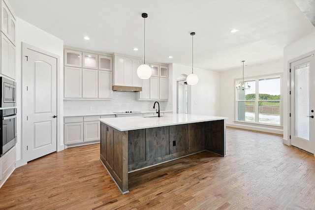 kitchen with sink, a kitchen island with sink, white cabinetry, and dark hardwood / wood-style flooring