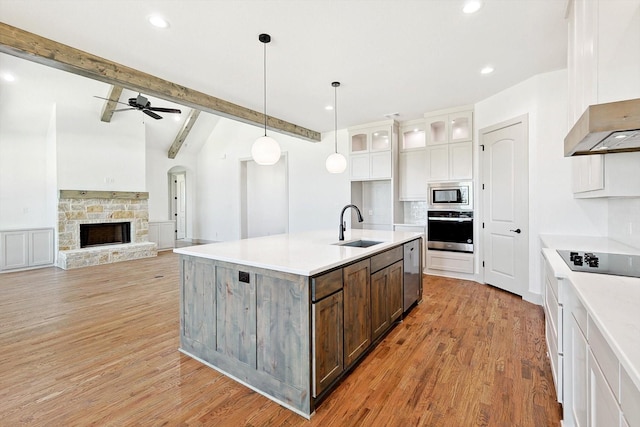 kitchen with white cabinets, decorative light fixtures, stainless steel appliances, sink, and a center island with sink