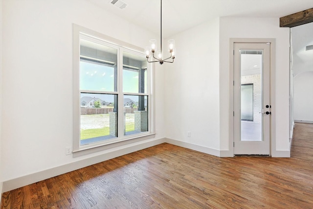 unfurnished dining area featuring wood-type flooring, an inviting chandelier, and beam ceiling