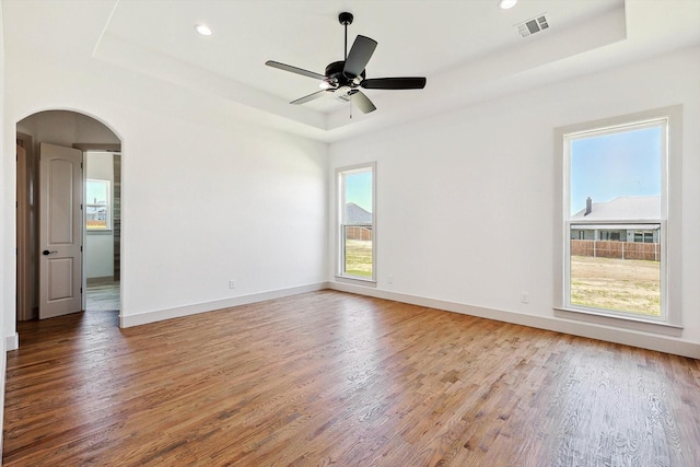 unfurnished room with hardwood / wood-style floors and a tray ceiling