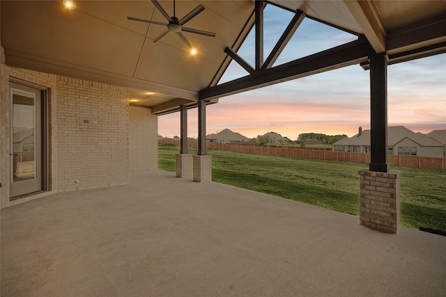 patio terrace at dusk featuring a lawn and ceiling fan