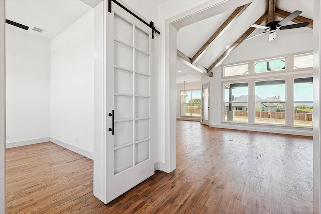 interior space with hardwood / wood-style floors, lofted ceiling with beams, ceiling fan, and a barn door