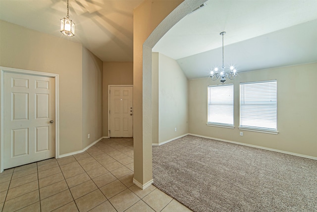 carpeted empty room featuring lofted ceiling and an inviting chandelier