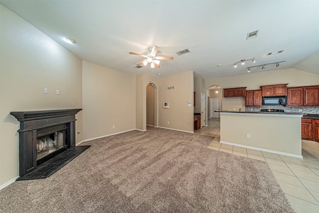 kitchen featuring ceiling fan, light tile floors, tasteful backsplash, rail lighting, and vaulted ceiling