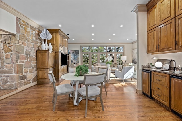 dining area featuring crown molding, wood-type flooring, and sink