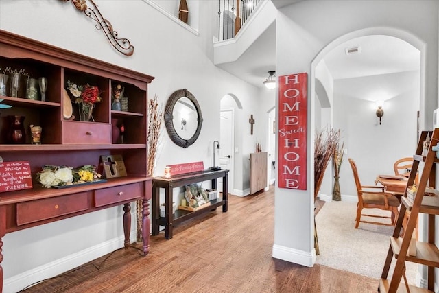 interior space featuring a towering ceiling and hardwood / wood-style flooring