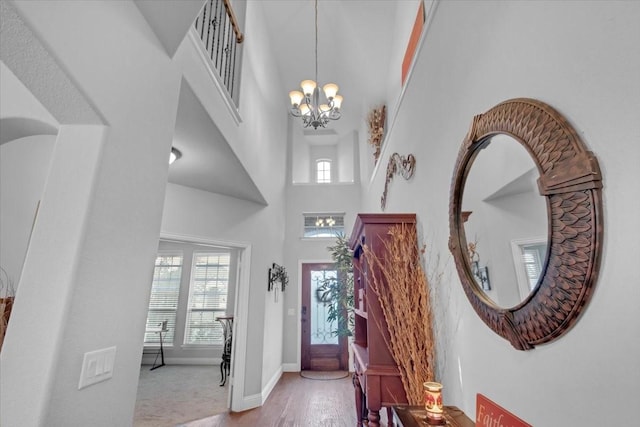 foyer featuring light wood-type flooring, a towering ceiling, and an inviting chandelier