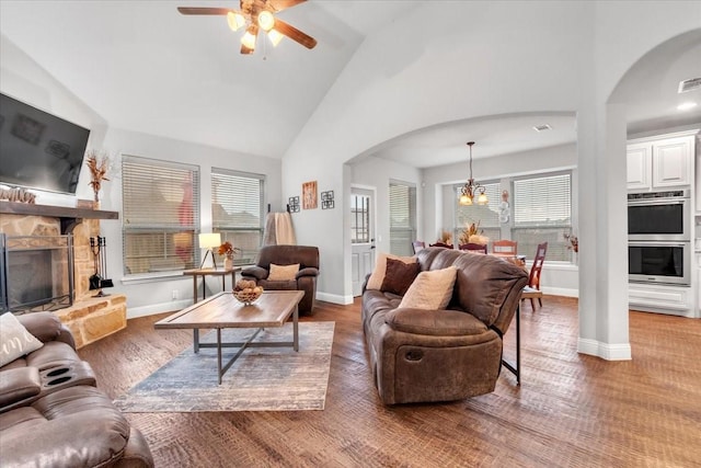 living room with a wealth of natural light, a fireplace, ceiling fan with notable chandelier, and hardwood / wood-style flooring