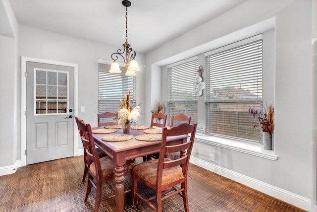 dining space with dark wood-type flooring and an inviting chandelier