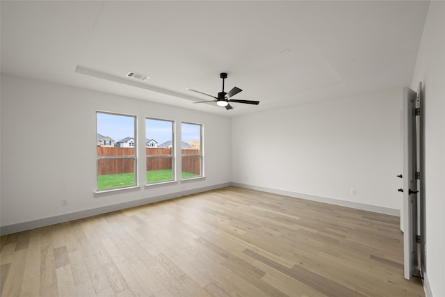 spare room featuring ceiling fan, a raised ceiling, and light wood-type flooring