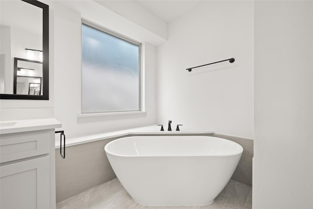 bathroom featuring a tub to relax in, vanity, and tile walls