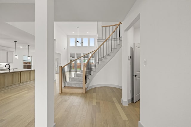 entryway featuring a high ceiling, light wood-type flooring, a chandelier, and sink