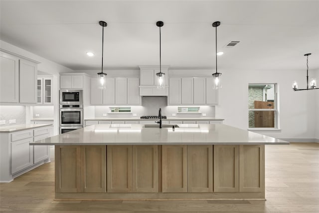 kitchen with a large island, appliances with stainless steel finishes, white cabinets, and decorative light fixtures