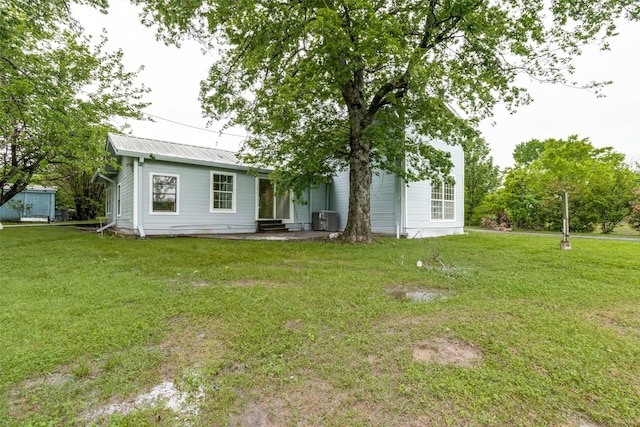 rear view of property featuring central AC unit and a yard