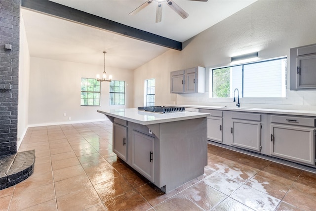 kitchen featuring sink, gray cabinets, hanging light fixtures, a kitchen island, and stainless steel gas stovetop