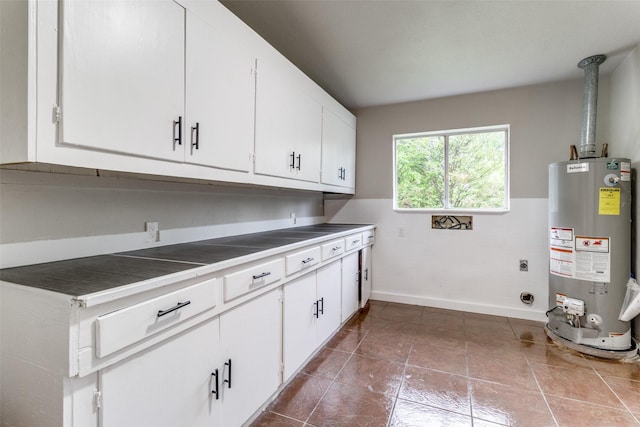 clothes washing area featuring cabinets, electric dryer hookup, tile patterned flooring, and gas water heater