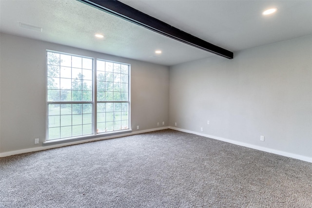 unfurnished room with beamed ceiling and carpet