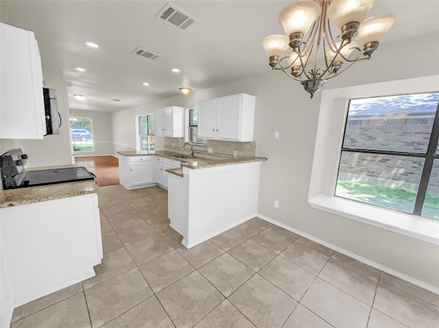 kitchen with white cabinets, stove, kitchen peninsula, an inviting chandelier, and decorative light fixtures