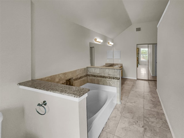 bathroom featuring vanity, vaulted ceiling, and a bath