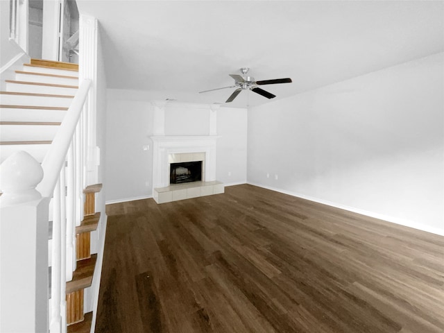 unfurnished living room featuring ceiling fan, a tile fireplace, and dark wood-type flooring