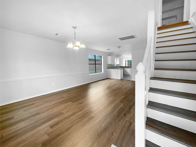 stairs featuring wood-type flooring and a chandelier