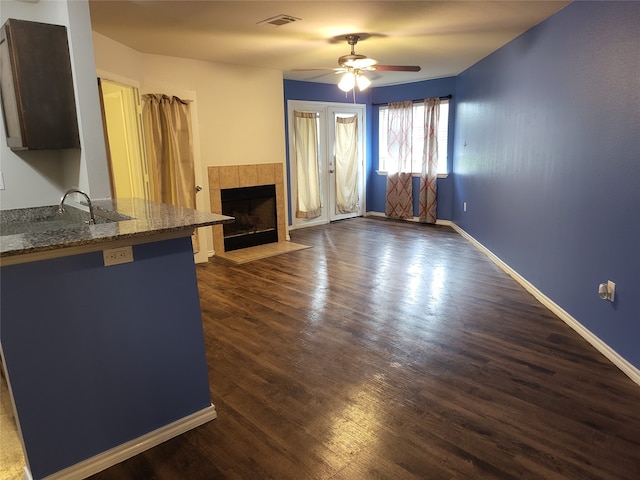 unfurnished living room with dark hardwood / wood-style flooring, ceiling fan, sink, and a fireplace