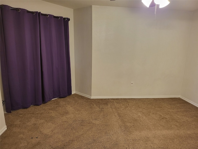 spare room featuring ceiling fan and dark colored carpet