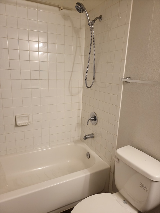 bathroom with tiled shower / bath combo and toilet