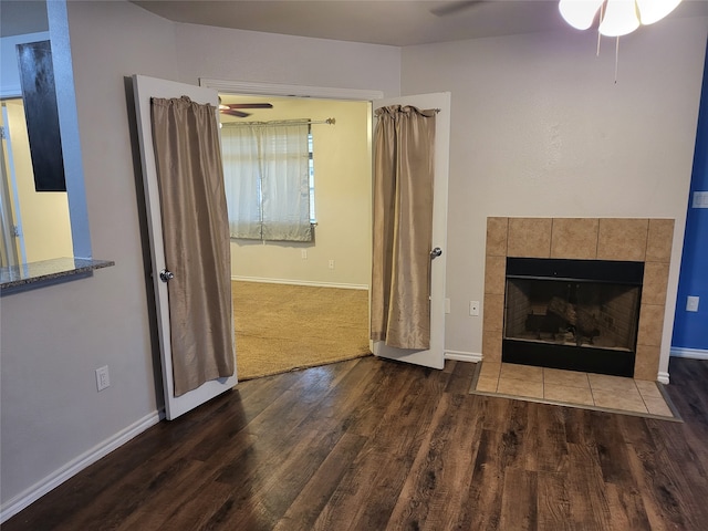 unfurnished living room with dark colored carpet, ceiling fan, and a tiled fireplace