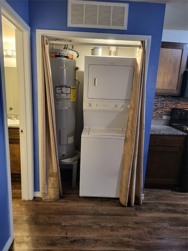 laundry area with dark hardwood / wood-style flooring, water heater, and stacked washer and dryer