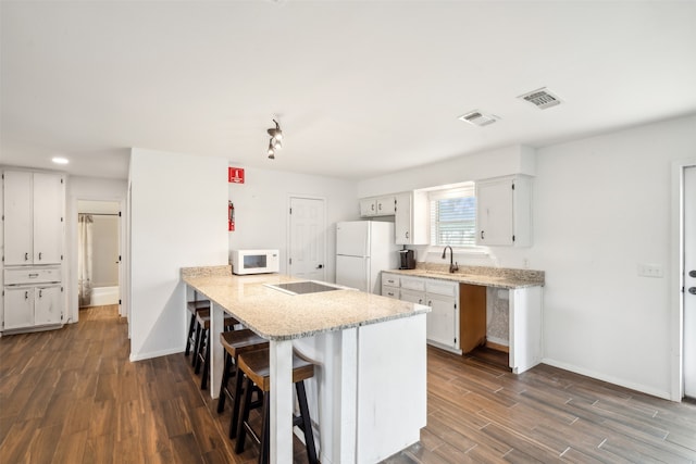 kitchen with a kitchen bar, wood-type flooring, white appliances, and sink