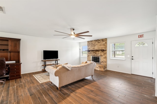 living room with ceiling fan, a fireplace, dark hardwood / wood-style flooring, and brick wall