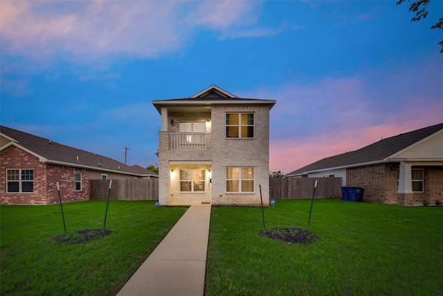 view of front facade featuring a balcony and a yard