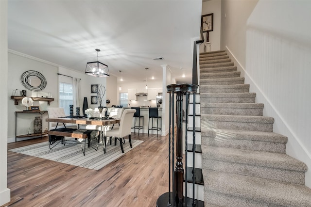 dining room featuring crown molding, hardwood / wood-style flooring, and a chandelier