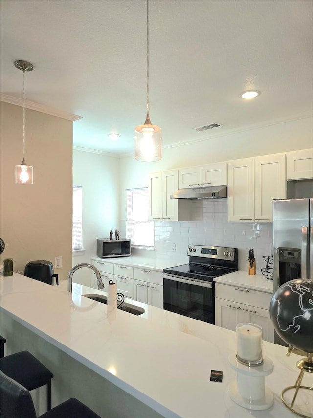 kitchen with white cabinetry, appliances with stainless steel finishes, pendant lighting, and backsplash