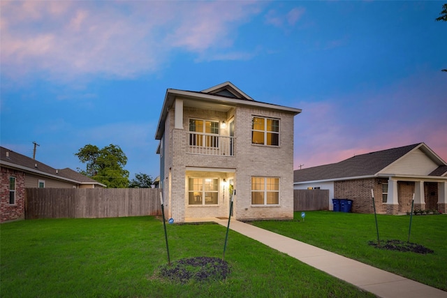 view of front of house featuring a balcony and a yard