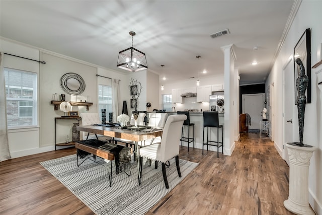 dining space with wood-type flooring, crown molding, a wealth of natural light, and a chandelier