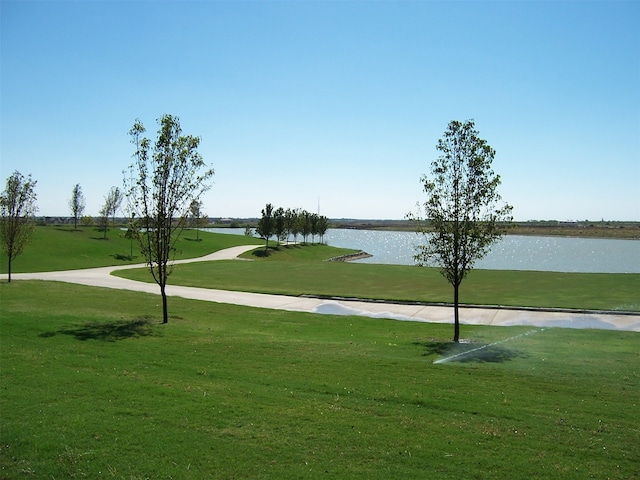 view of property's community with a water view and a lawn