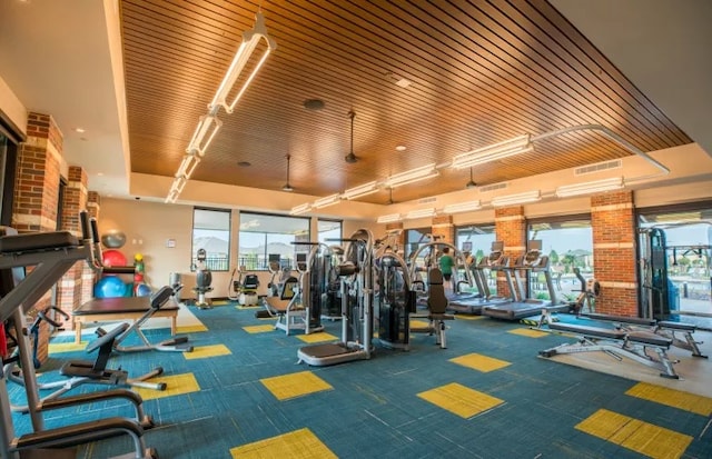 workout area featuring a wealth of natural light, wooden ceiling, brick wall, and carpet floors