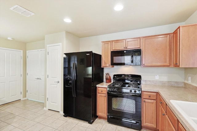 kitchen featuring sink, black appliances, and light tile floors