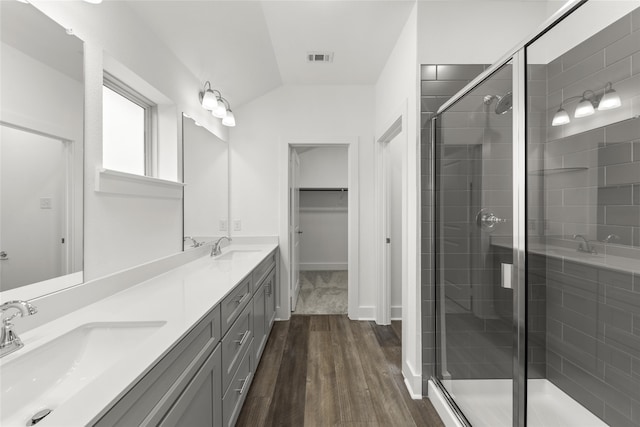 bathroom with dual vanity, lofted ceiling, an enclosed shower, and hardwood / wood-style floors