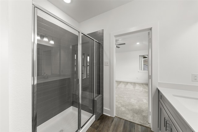 bathroom featuring ceiling fan, walk in shower, vanity, and wood-type flooring