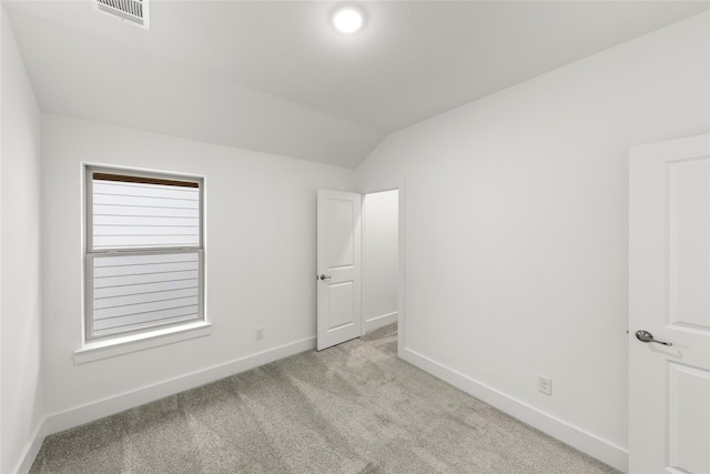 spare room featuring vaulted ceiling and light colored carpet