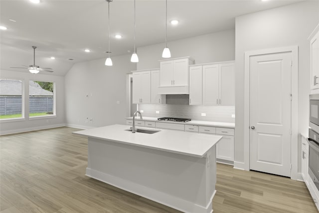 kitchen featuring light wood-type flooring, backsplash, sink, ceiling fan, and vaulted ceiling